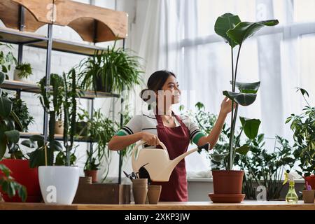 Eine asiatische Frau auf einer Schürze bewässert in ihrem Blumenladen. Stockfoto
