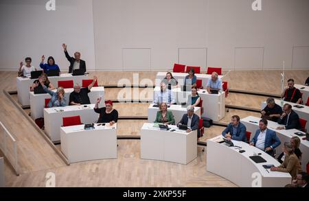 Potsdam, Deutschland. Juli 2024. Mitglieder der Fraktion die Linke heben bei einer Abstimmung im landtag die Hände. Am Mittwoch wird das landhaus das Hilfspaket für die Folgen des Krieges in der Ukraine mit einem neuen Nachtragshaushalt genehmigen. Quelle: Hannes P. Albert/dpa/Alamy Live News Stockfoto