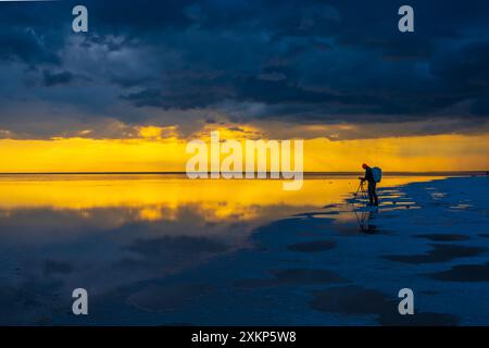 Der Fotograf fängt den faszinierenden Sonnenuntergang und seine Reflexion über dem ruhigen Wasser ein und schafft eine wunderschöne und ruhige Szene. Stockfoto