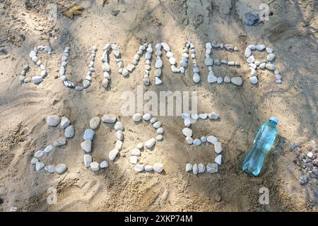 Text Sommer 2025 geschrieben mit Kieselsteinen auf dem Sand am Strand und einer Wasserflasche, Symbol für Freizeit, Meeresurlaub und genug Trinken im warmen Wetter Stockfoto