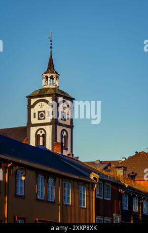 Sonnenuntergänge beleuchten die bezaubernde Landschaft von Roros, mit der Wahrzeichen der Stadt Kirche und Holzarchitektur Stockfoto