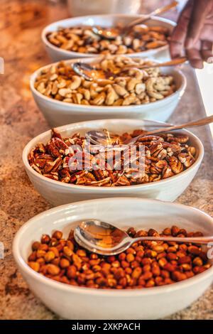 Erdnüsse, Cashewnüsse, Mandeln, Walnüsse, verschiedene Schalen auf einem Marmortisch Stockfoto