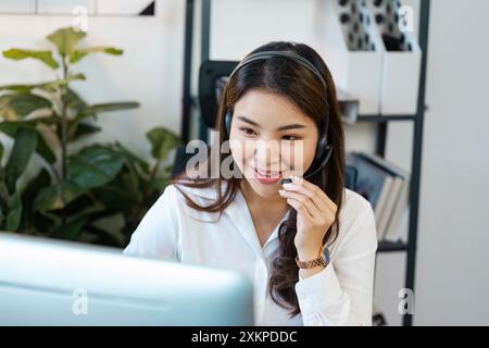 Lächelnder Callcenter-Agent mit Headset, der den Kundendienst in einer modernen Büroumgebung bietet Stockfoto