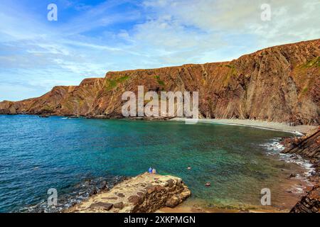 Schwimmer in der Bucht unter den dramatischen, gefalteten Gesteinsschichten aus Schlamm- und Sandsteinen am Hartland Quay auf dem SW Coast Footpath in Devon, England, Großbritannien Stockfoto