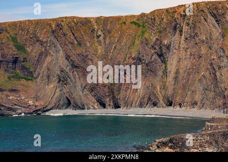 Schwimmer in der Bucht unter den dramatischen, gefalteten Gesteinsschichten aus Schlamm- und Sandsteinen am Hartland Quay auf dem SW Coast Footpath in Devon, England, Großbritannien Stockfoto