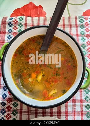 Herzhafte hausgemachte Gemüsesuppe in einer rustikalen Schüssel auf gemusterter Tischdecke. Ungarisches Essen. Stockfoto