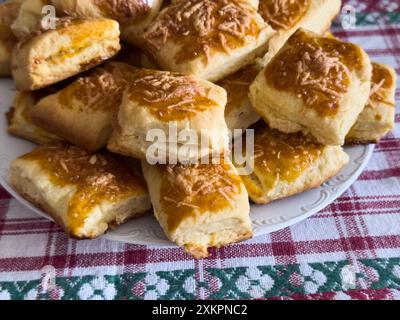 Eine Nahaufnahme eines Tellers gefüllt mit frisch gebackenen Käsescones auf einer farbenfrohen karierten Tischdecke. Stockfoto