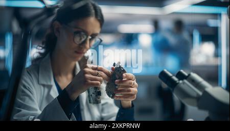 Fokussierte professionelle Ingenieurin, die an elektronischen Leiterplatten arbeitet. Industrierobotik-Spezialisten für Labormäntel entwickeln mobilen KI-Roboter in einer Fabrik für fortgeschrittene Technologien. Stockfoto