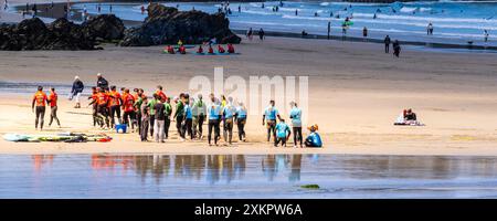 Ein Panoramabild eines Sonnenlichts auf einer Gruppe von Urlaubern, die sich auf eine Surfstunde am GT Great Western Beach in Newquay in Cornwa vorbereiten Stockfoto
