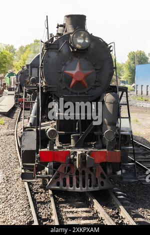 Schwarze Dampflokomotive mit rotem Stern aus der UdSSR-Zeit Nahaufnahme von vorne, vertikales Foto am Hauptbahnhof von Sortavala an einem sonnigen Sommer Stockfoto
