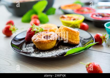 Süße Quark-Muffins mit Erdbeerfüllung, auf einem Teller auf einem Holztisch. Stockfoto