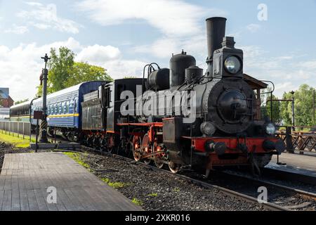 An einem sonnigen Sommertag fährt der Oldtimer-Personenzug mit schwarzer Dampflokomotive auf dem Hauptbahnhof von Sortavala Stockfoto