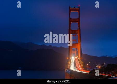 Nachtansicht auf die Golden Gate Bridge mit leichten Wegen, die von vorbeifahrenden Fahrzeugen hinterlassen werden. Blaue Stunde. Stockfoto