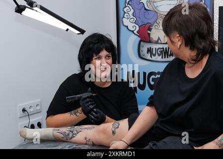 Alcoy, Spanien, 17.07.2024; Tätowierer lächelt, bevor er die Haut durchstochen und Schmerzen verursacht Stockfoto