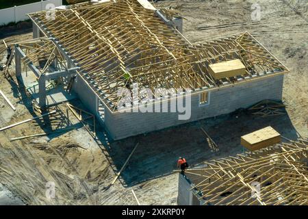 Luftaufnahme von Bauunternehmern, die an einem unfertigen Wohnhaus mit Holzdachrahmen arbeiten, der im Vorstadtbereich Floridas im Bau ist Stockfoto
