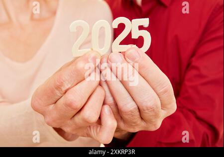 Zwei Seniorenhände, die das Jahr 2025 als Zahl anzeigen Stockfoto