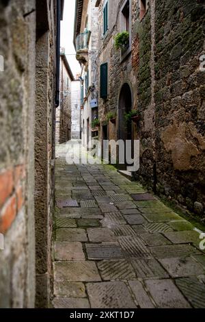 Eine schmale, schwach beleuchtete, gekachelte Straße, zwischen den Steinhäusern, Monte Amiata Gegend, Siena, Toskana, Italien Stockfoto