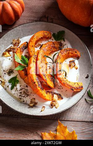 Gebratener Kürbis mit griechischem Joghurt und Kräutern aus nächster Nähe. Warmer, würziger Kürbissalat mit weichem Ziegenkäse, Labneh Cream Chese. Stockfoto
