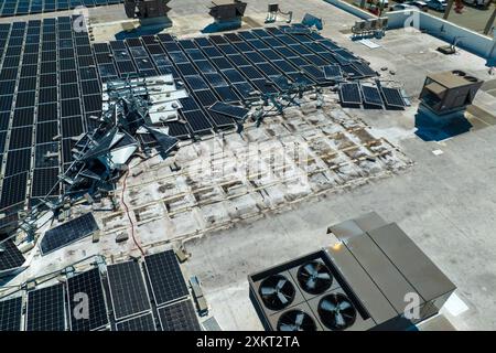 Draufsicht der durch den Hurrikan Ian zerstörten Photovoltaik-Solarpaneele, die auf dem Dach des Industriebaues zur Erzeugung von ökologischem Strom montiert sind Stockfoto