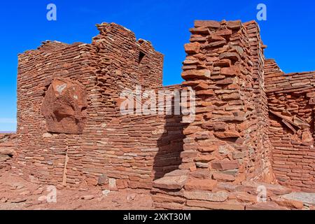 Hohe, mehrstöckige Pueblo-Ruinen aus Sandsteinblöcken, die sich vor dem hellblauen Himmel am Wupatki National Monument befinden Stockfoto