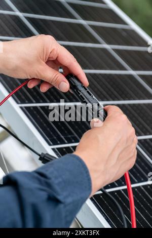 Nahaufnahme der Hände des Technikers, die mc4-Steckverbinder über dem Solarpanel verbinden. Erneuerbare Energien und Nachhaltigkeitskonzept Stockfoto