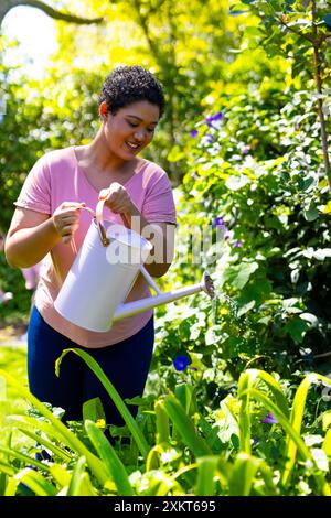 Genießen Sie Gartenarbeit im Freien, Frau bewässert Pflanzen im Garten Stockfoto