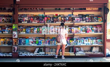 Eine Frau, die Zeitschriften im Regal eines Zeitungskiosk oder eines Zeitungskiosk am Straßenrand in Südkalifornien, USA, ansieht Stockfoto