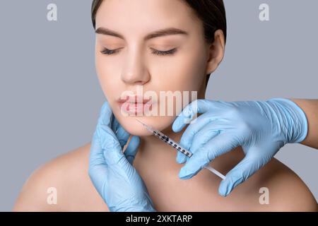 Kosmetikerin injiziert in einem Schönheitssalon die Lippen und die Nasolabialfalten einer schönen Frau. Frauenkosmetologie im Schönheitssalon. Stockfoto