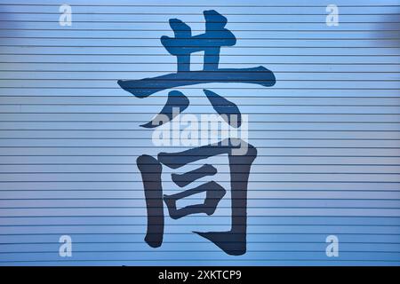 Handgemalte chinesische Schriftzeichen auf blauer Metalloberfläche, Tageslichtperspektive Stockfoto