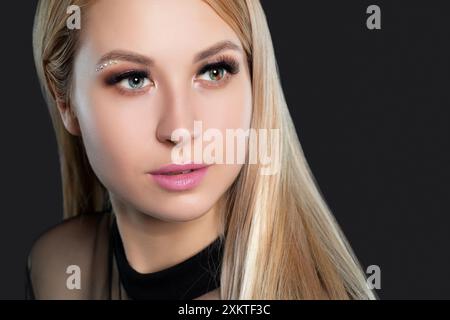 Blaugrünes Auge der Frau mit Heterochromie der Pupille, mit langen blonden Haaren mit wunderschönem Make-up und dicken Augenbrauen. Blick auf die Kamera. Professionell m Stockfoto