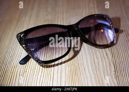 Eine elegante Sonnenbrille aus schwarzem Katzenaugen auf einem Holztisch, die Stil und Raffinesse demonstriert Stockfoto