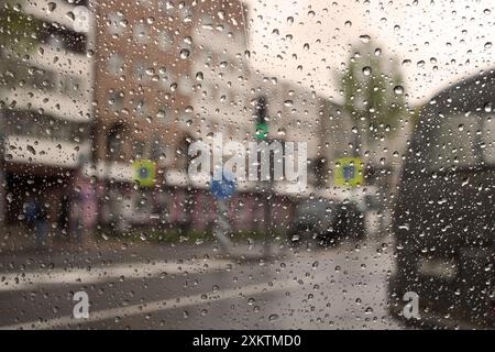 Regentropfen auf der Windschutzscheibe auf Stadtstraße Hintergrund Makrofotografie Stockfoto