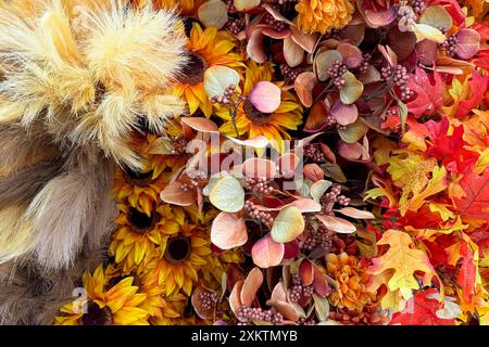 Künstliche Blumen und Laub im Herbst-Stil mit Sonnenblumen, getrockneten Gräsern und bunten Blättern Stockfoto