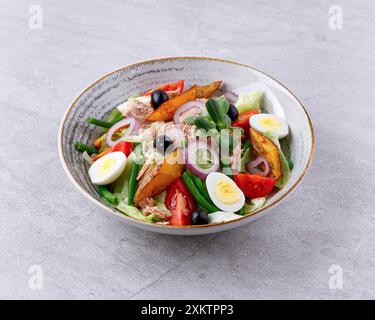 Salat mit Thunfisch aus der Dose, Salat Nicoise, auf grauem Hintergrund für ein Menü auf der Essensseite Stockfoto