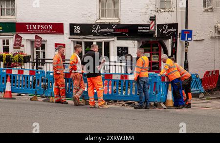 Eine Gruppe von Bauarbeitern in gut sichtbarer Kleidung, die um einen ausgegrabenen Bereich auf einer Straße stehen und die laufenden Arbeiten besprechen. Marlborough Wilts Stockfoto