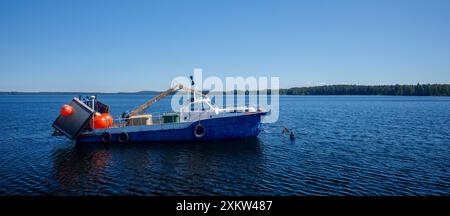 Kleiner finnischer Binnensee-Trawler, der hinter dem Seegang am See Pohjois-Konnevesi in Finnland ankert Stockfoto