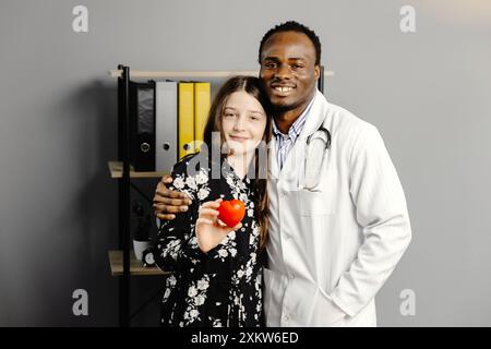 Mann in weißem Gewand und Mädchen stehen zusammen, Mädchen mit rotem Herzen. Stockfoto