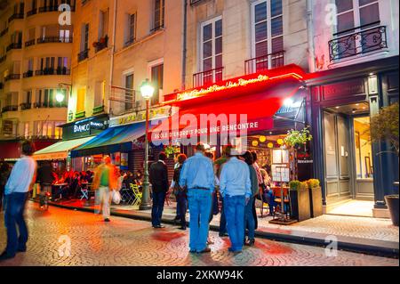 Paris, Frankreich, Menschenmenge, Männer, Drinks draußen teilen, auf der Straßenszene bei Nacht, Ladenfronten, Straßenlaternen, Rue Montorgeuil Stockfoto