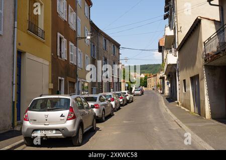 Langeac, Frankreich - 28. Mai 2023: Eine Straße, gesäumt von Parkwagen in der malerischen Stadt Langeac, Frankreich. Die Sonne scheint hell und wirft Schatten Stockfoto