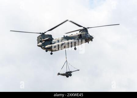 RAF Boeing Chinook Hubschrauber mit mittlerem Aufzug, der eine untersackte Last eines Feldgewehrs auf der Farnborough International Airshow 2024, Großbritannien, transportierte. Stockfoto