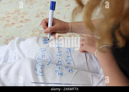 Mädchen, das Mathematik macht, sitzt auf dem Boden, schreibt auf Whiteboard mit Stift Algebra erweitert Quadratik Klammern Mathematik Mathematik Bildung Mädchen in MINT Stockfoto