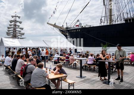 MARIEHAMN, Åland, FINNLAND - 24. JULI 2024: Besucher essen vor dem Museumsschiff Pommern im Restaurant Kvarter5. Tag 1 der dreitägigen Åland-Etappe des Tall Ships Race 2024 im Haupthafen, Mariehamn, Åland, Finnland. Foto: Rob Watkins/Alamy Live News. INFO: Das Tall Ships Race ist eine jährliche Segelveranstaltung mit historischen und modernen Großschiffen. Es fördert internationale Freundschaft und Jugendausbildung und zieht Teilnehmer und Zuschauer weltweit an, um maritimes Erbe und die Kunst des traditionellen Segelns zu feiern. Stockfoto