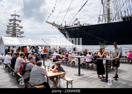 MARIEHAMN, Åland, FINNLAND - 24. JULI 2024: Besucher essen vor dem Museumsschiff Pommern im Restaurant Kvarter5. Tag 1 der dreitägigen Åland-Etappe des Tall Ships Race 2024 im Haupthafen, Mariehamn, Åland, Finnland. Foto: Rob Watkins/Alamy Live News. INFO: Das Tall Ships Race ist eine jährliche Segelveranstaltung mit historischen und modernen Großschiffen. Es fördert internationale Freundschaft und Jugendausbildung und zieht Teilnehmer und Zuschauer weltweit an, um maritimes Erbe und die Kunst des traditionellen Segelns zu feiern. Stockfoto