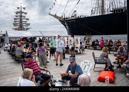 MARIEHAMN, Åland, FINNLAND - 24. JULI 2024: Besucher essen vor dem Museumsschiff Pommern im Restaurant Kvarter5. Tag 1 der dreitägigen Åland-Etappe des Tall Ships Race 2024 im Haupthafen, Mariehamn, Åland, Finnland. Foto: Rob Watkins/Alamy Live News. INFO: Das Tall Ships Race ist eine jährliche Segelveranstaltung mit historischen und modernen Großschiffen. Es fördert internationale Freundschaft und Jugendausbildung und zieht Teilnehmer und Zuschauer weltweit an, um maritimes Erbe und die Kunst des traditionellen Segelns zu feiern. Stockfoto