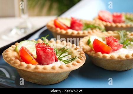 Köstliche Canapes mit trockenen geräucherten Würstchen, Frischkäse und Gemüse auf dem Tisch, Nahaufnahme Stockfoto