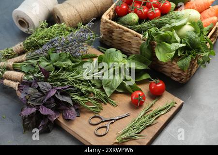 Verschiedene aromatische Kräuter, Gemüse und Scheren auf grauem Tisch, Nahaufnahme Stockfoto