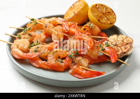 Köstliche gegrillte Garnelenspieße, Zitrone und Knoblauch auf weißem Tisch, Nahaufnahme Stockfoto