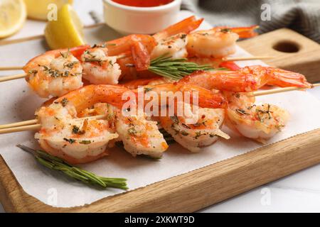 Spieße mit köstlichen gegrillten Garnelen auf weißem Tisch, Nahaufnahme Stockfoto