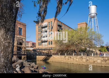 Waveshaper Island Blick auf das Eagle & Phenix Mills Gebäude und den Wasserturm entlang des Chattahoochee River in Uptown Columbus, Georgia. (USA) Stockfoto