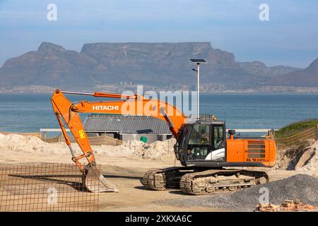 Nahaufnahme eines HITACHI Baggers auf einer Baustelle in Bloubergstrand, Kapstadt. Tafelberg im Hintergrund. Stockfoto